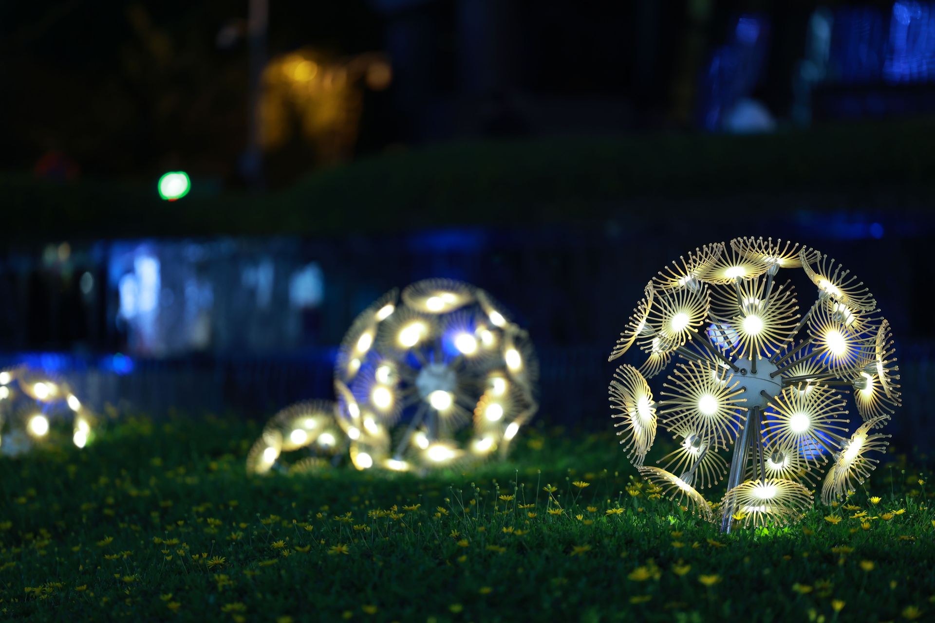 Artistic glowing spheres illuminate a garden at night, creating a magical atmosphere.